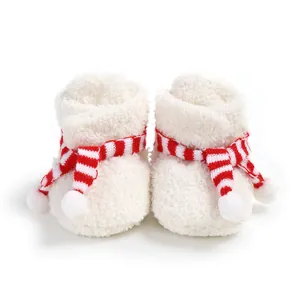 Detail of white fuzzy baby booties with a festive red striped scarf decoration