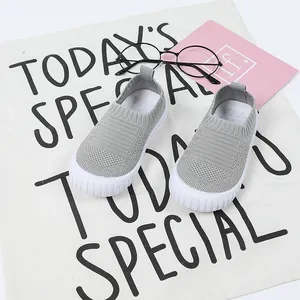 Graue atmungsaktive Flyknit-Kinderschuhe in einem stilvollen Lifestyle-Hintergrund.