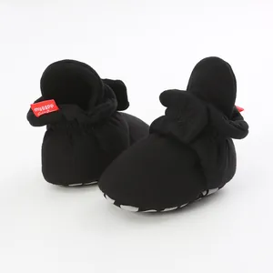Detailed view of black baby soft sole pre-walker booties with non-slip grip and red tag