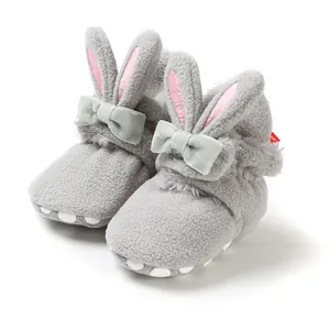 Detailopname van grijze pluche babyschoentjes met konijnenoren en een zachte strik.
