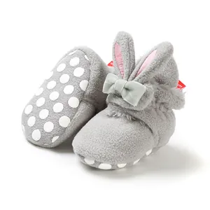 Detailweergave van grijze pluchen babyschoenen met konijnenoren en antislipzool