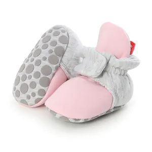 Detail of soft-soled baby booties showing anti-slip dots and pink cotton fabric texture.