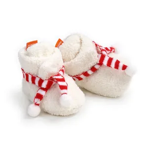 Detailed view of white fluffy baby Christmas booties with red striped scarf decoration