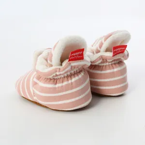 Close-up detail of baby booties with pink striped knit fabric and soft white fleece lining