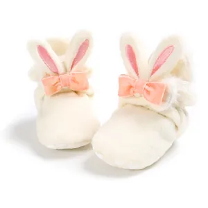 Detail van zachte baby-fleece schoenen met roze konijnenoren en een perzik strik
