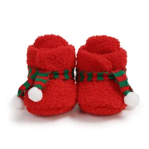 Detailed view of red plush Christmas baby boots with green striped scarf decor