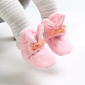 Detailopname van roze fleece babyschoentjes met konijnenoren en strikjes op babyvoetjes