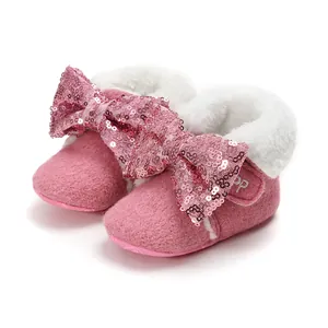 Detailaufnahme von rosa Baby-Winterstiefeln mit einer großen, glitzernden Paillettenschleife