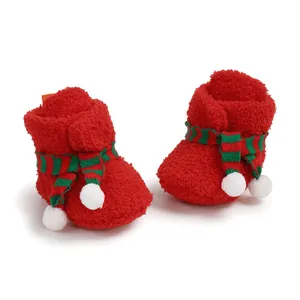 Detailed view of red fuzzy Christmas baby boots with striped scarf and white pom-poms