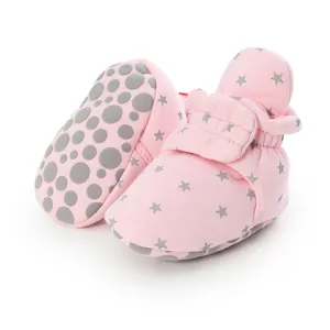 Detailed view of soft pink baby booties with star pattern and anti-slip rubber sole