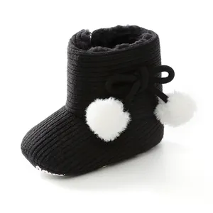 Gros plan de bottes d'hiver noires pour bébé avec pompons blancs et maille douce