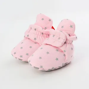 Close-up of soft pink baby walker shoes with grey star patterns and velcro straps.