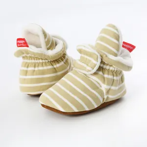 Detailed view of striped knitted baby booties with soft fleece lining and red tag.