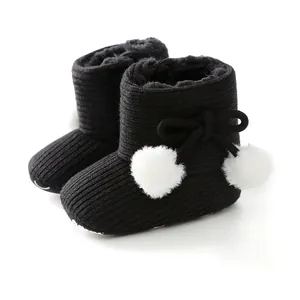 Gros plan de bottines tricotées pour bébé noires avec pompons doux et doublure polaire