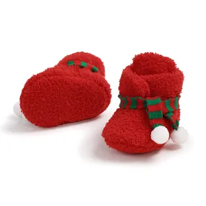 Close-up detail of red fuzzy Christmas baby booties with a green striped scarf decoration