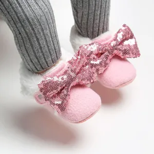 Detailaufnahme rosa Plüsch Baby-Schuhe mit Pailletten-Schleifen und Kunstfell.