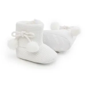 Détail de bottes d'hiver en tricot blanc pour bébé avec pompons duveteux et semelles souples