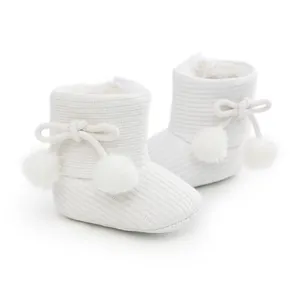 Gros plan de bottines tricotées pour bébé avec pompons et doublure chaude