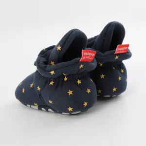 Close-up detail of navy blue baby walking shoes with gold star patterns and red brand tag