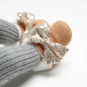 Detailansicht brauner Babyschuhe mit goldenen Paillettenschleifen und weißem Pelzfutter