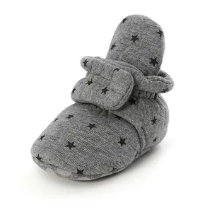 Close-up of gray baby bootie with black star pattern and soft knit texture.