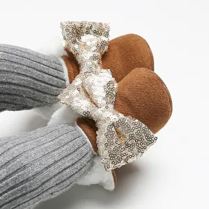 Nahaufnahme brauner Baby-Lauflernschuhe mit Pailletten-Schleife und weichem Fleecefutter