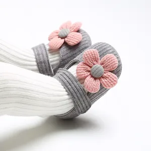 Close-up detail of grey knitted baby girl princess shoes with 3D pink flower