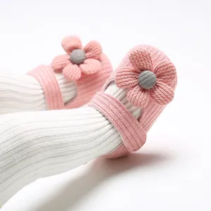 Close-up of pink knit baby shoes with 3D floral decoration and soft texture