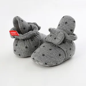 Close-up of grey baby soft sole sock shoes with black star pattern and red label
