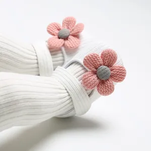 Close-up detail of soft white knitted baby girl princess shoes with pink flower accents
