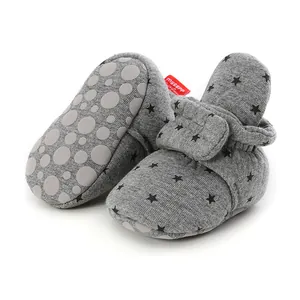 Detail of grey baby soft sole shoes with black star pattern and non-slip bottom.