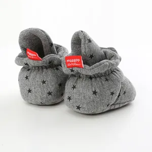 Detailed rear view of grey cotton baby booties with black star patterns and red tag