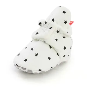 Detailed view of white baby sock shoe featuring black star pattern and soft sole