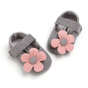 Detail view of grey knitted baby girl princess shoes featuring soft pink flower decoration