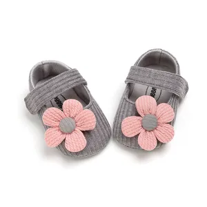 Detailed macro view of grey knitted soft-sole baby girl shoes with pink flower decoration