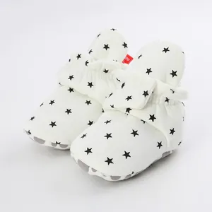 Detail view of white baby booties with black star pattern and soft anti-slip sole
