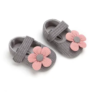 Close-up of grey knit baby girl shoes with decorative pink flowers and soft soles