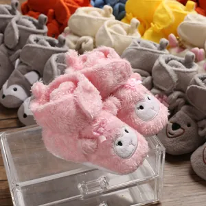 Dettaglio di scarpine in peluche per neonati con simpatici musi di animali e fiocchi
