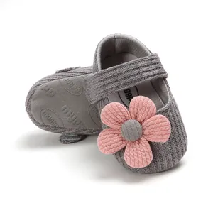 Close-up detail of gray knitted baby princess shoes with a pink flower decoration