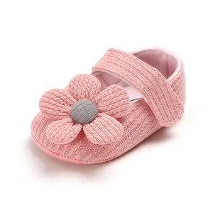 Detail shot of a soft pink knitted baby princess shoe with a cute flower decoration.