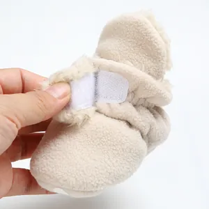 Close-up of beige fleece baby bootie showing the adjustable Velcro strap detail.