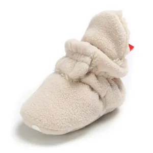 Close-up detail of warm cream fleece baby bootie with non-slip sole and soft elastic ankle