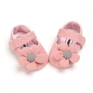Detail view of soft pink knitted baby girl shoes featuring a large 3D flower decoration