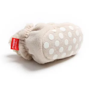 Close-up of soft beige fleece baby bootie with white non-slip polka dot sole