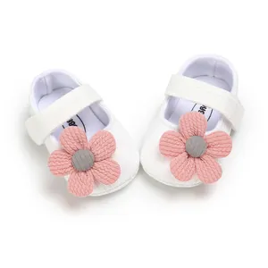 Detail view of white knitted baby princess shoes featuring large pink decorative flowers