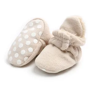 Close-up of warm beige fleece baby booties with anti-slip dotted soles