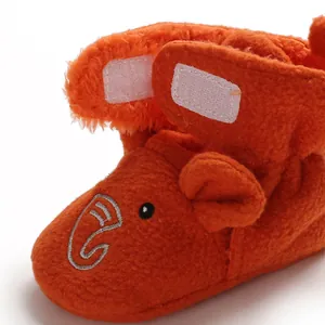 Dettaglio della morbida texture in pile e del ricamo di elefante sulle scarpe neonato arancioni