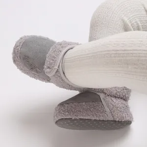 Detail showing grey winter baby snow boots with 'Baby' embroidery and soft fleece texture.