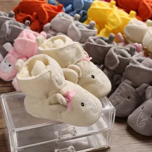 Primo piano di scarpine primi passi in peluche con ricamo a elefante e fiocco rosa