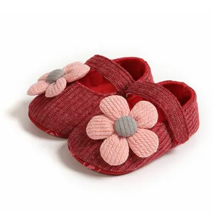 Detailed macro view of red knitted baby girl princess shoes featuring a large pink flower
